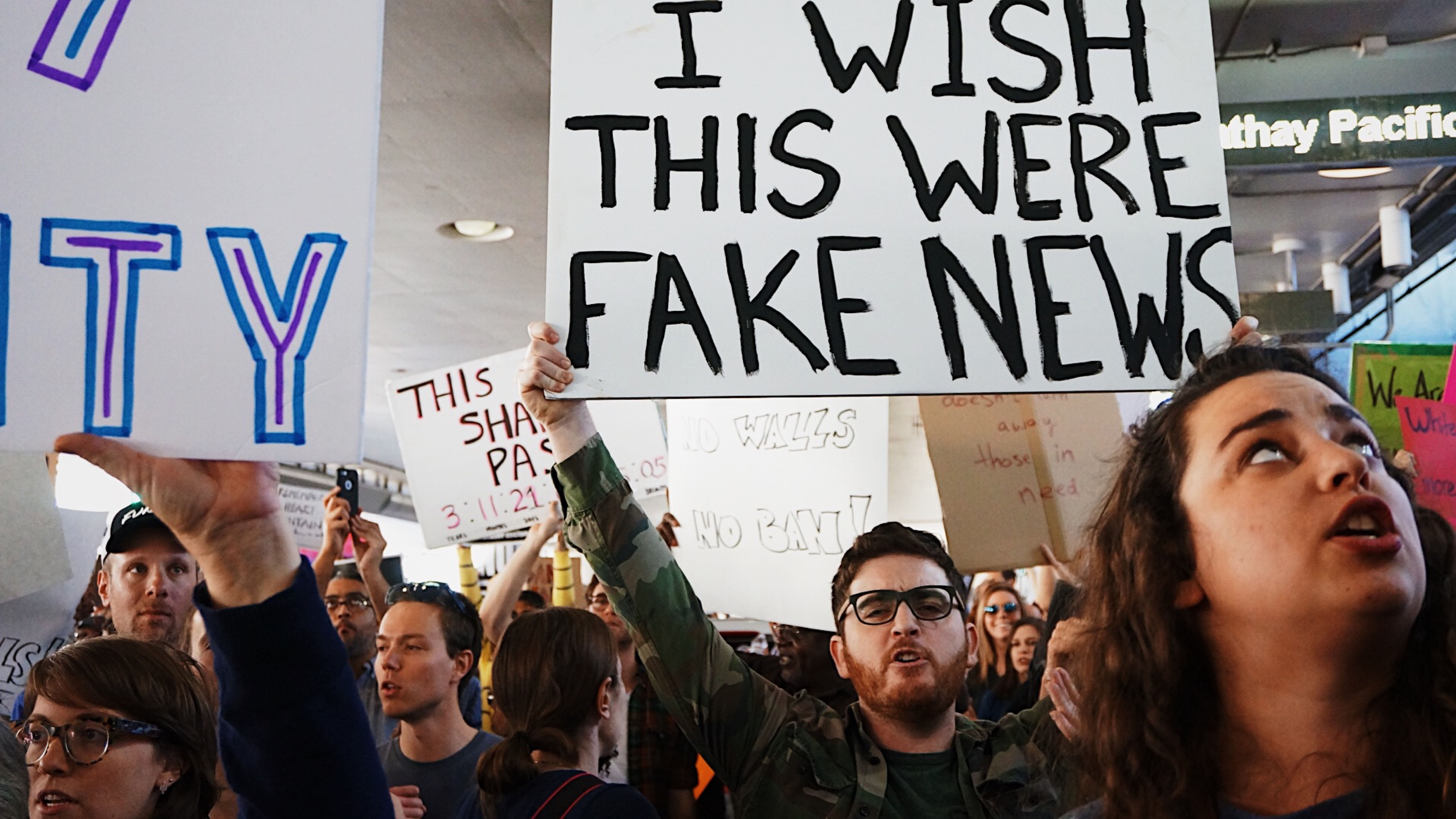 pessoas em protestos com placas escrito fake news